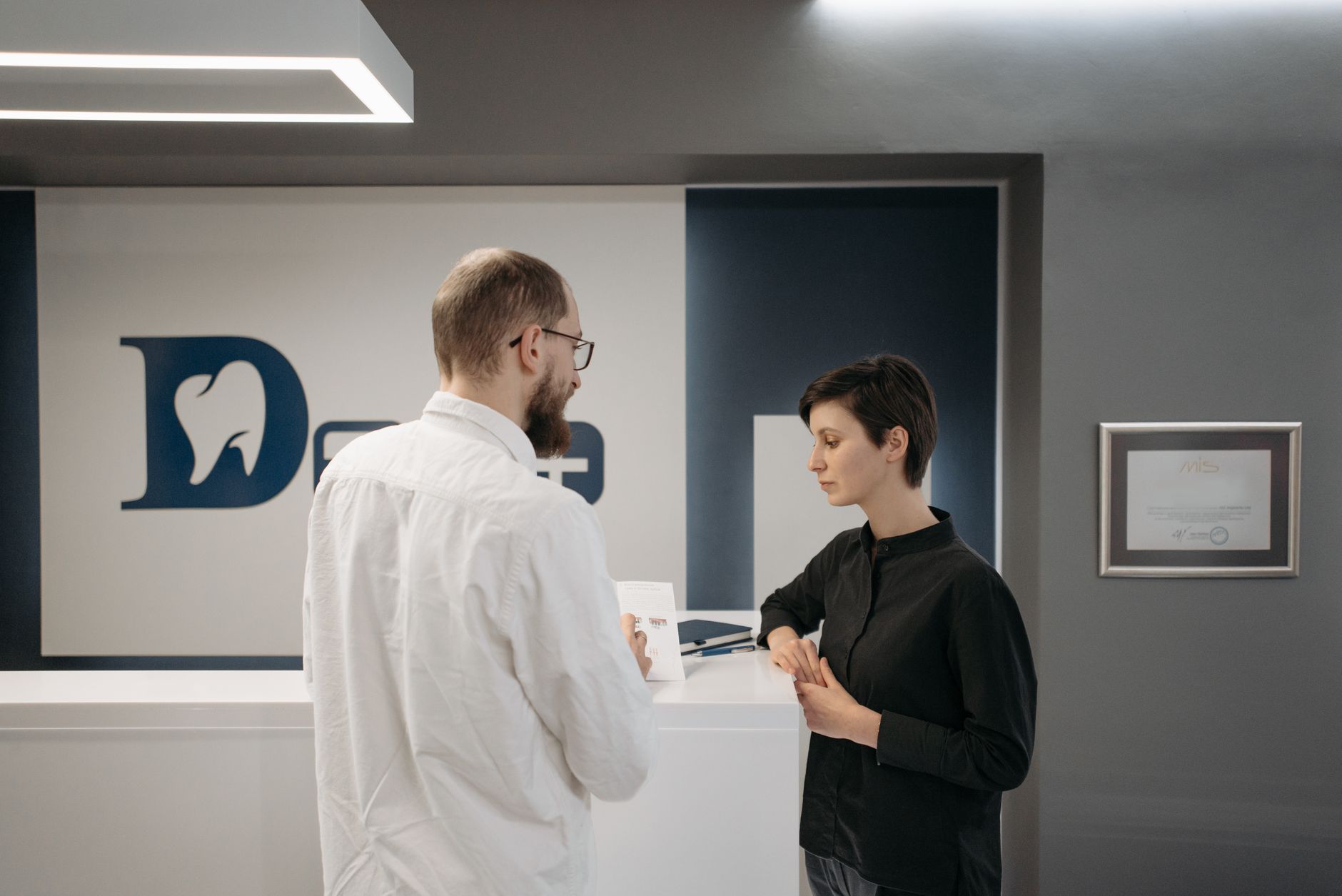 A dentist consulting a patient at a modern dental clinic reception.